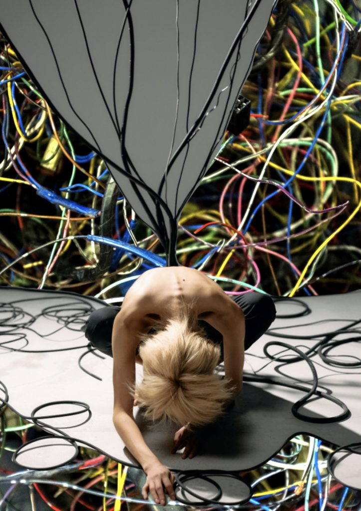 A digital collage representing nerve pain and damage. There is a person at the centre of the image lying in a ball and it appears as though large wires are growing from their spine.