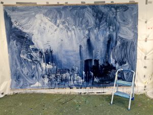 Photograph taken in my studio.First stage of painting, dark blue washes of acrylic paint staining the canvas.