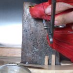 Cutting red bird's head sculpture in studio