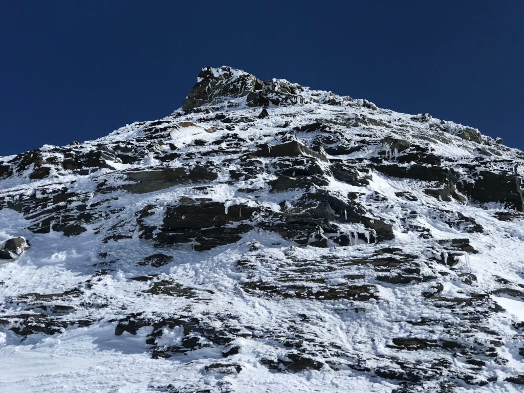 Blue sky background with snowy rocky mountains in foreground