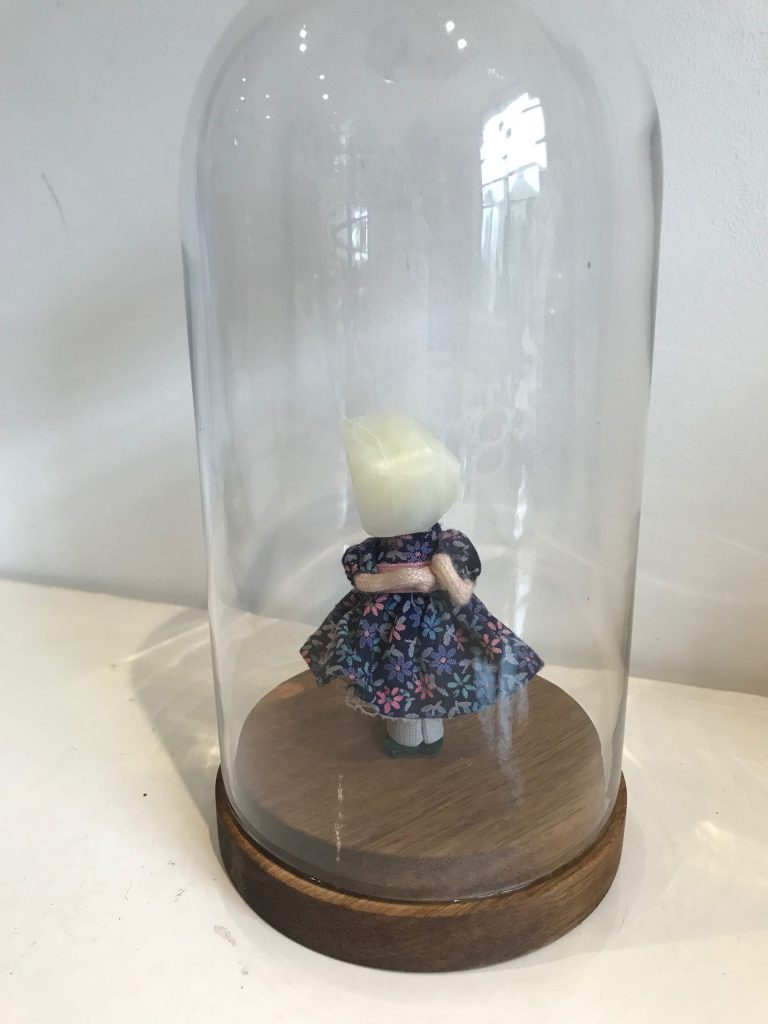 Woman rock hybrid in a glass dsiplay- girl in blue floral dress and rock head sculpture