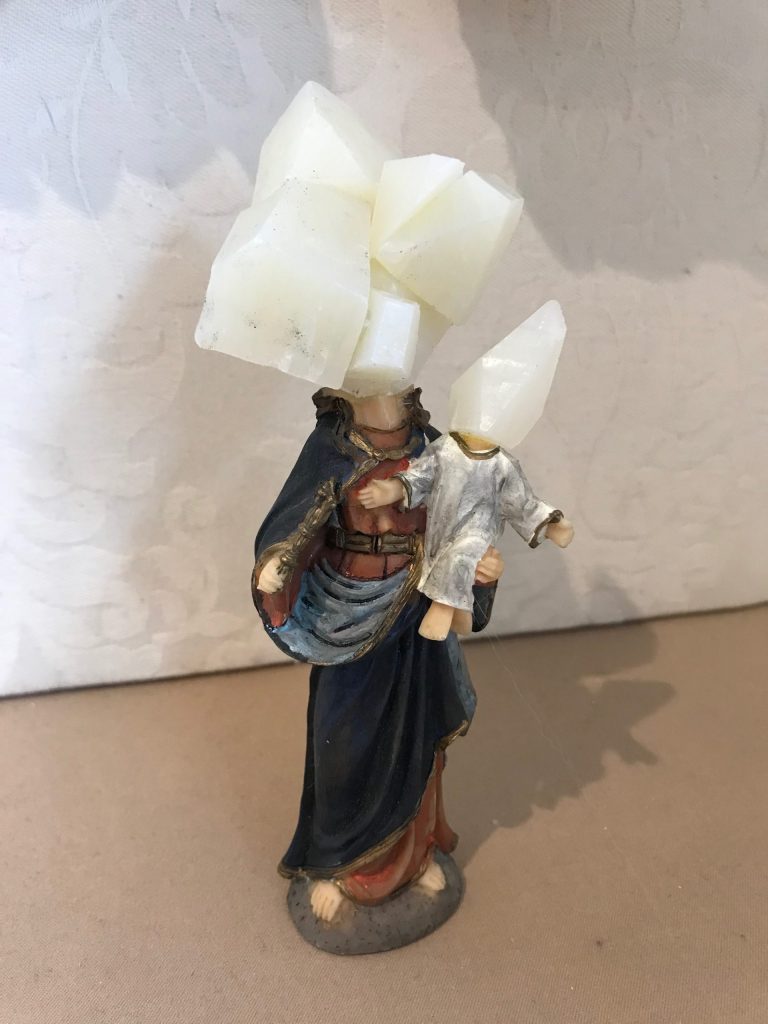 Woman rock hybrid in a glass dsiplay- woman in drape holding a baby with soap head sculpture