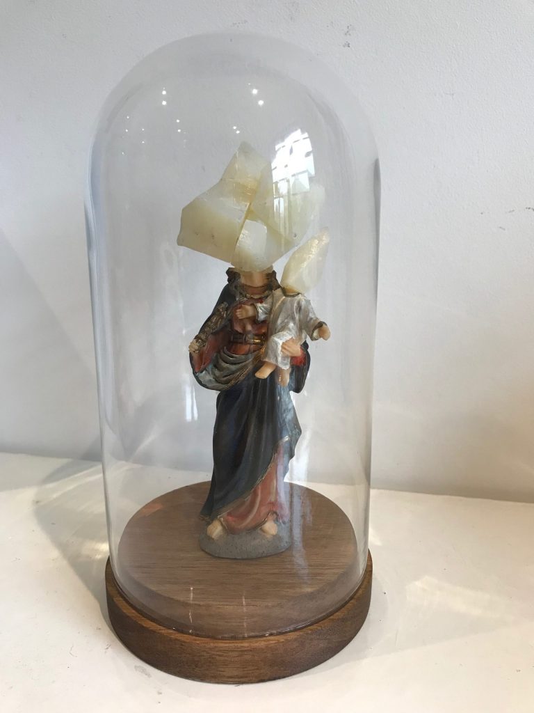 Woman rock hybrid in a glass dsiplay- woman in drape holding a baby with soap head sculpture