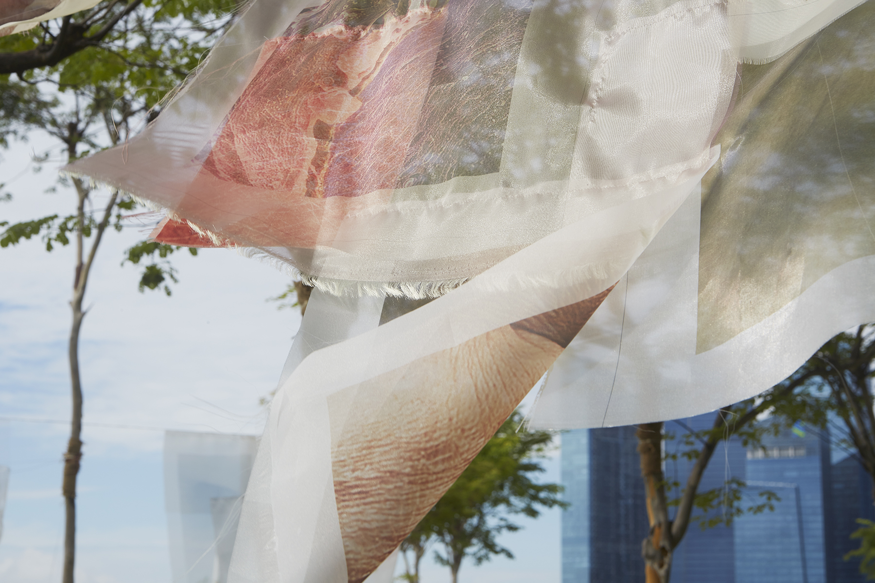 Close up of one of the fabric installation - with trees and blue building in the background