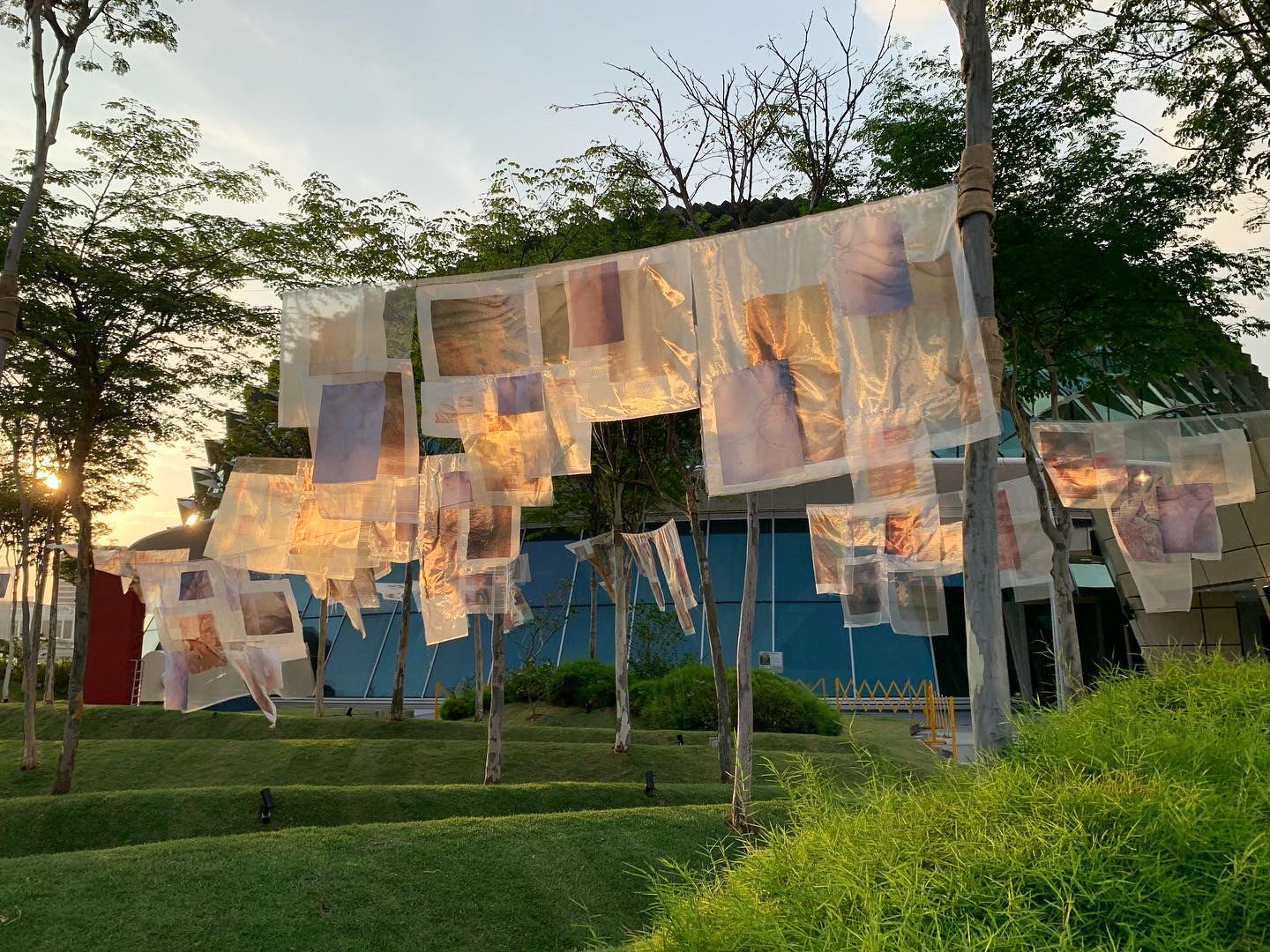 A hanging of different neutral-coloured fabric installation on trees in an open garden in Singapore.