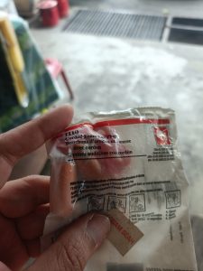 holding a packet of unopened corded foam earplugs.