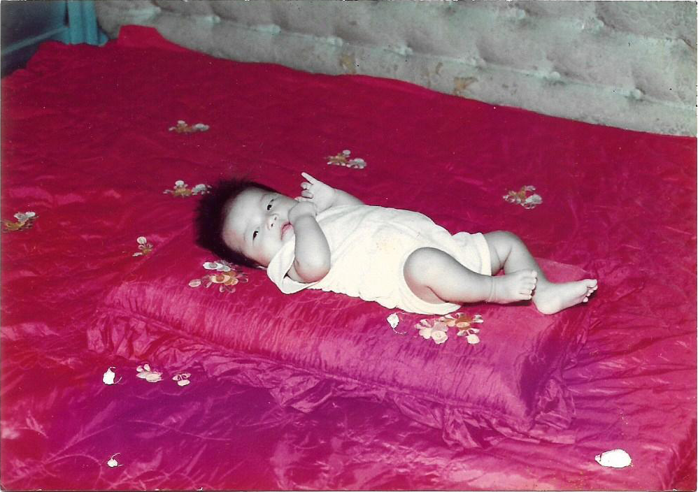 Digitised photograph of a baby on a red bed.